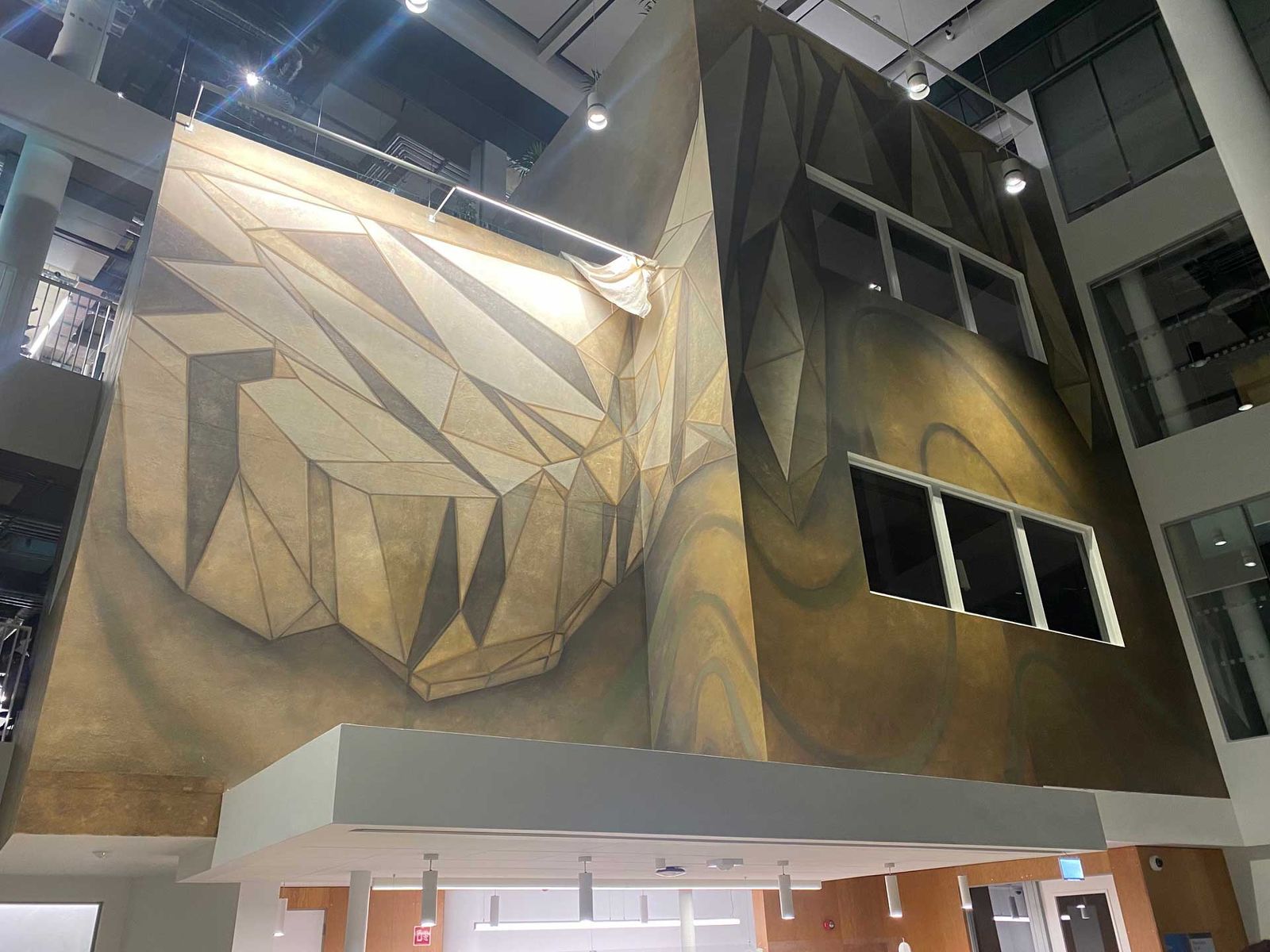 Faceted metal feature wall rising through an atrium