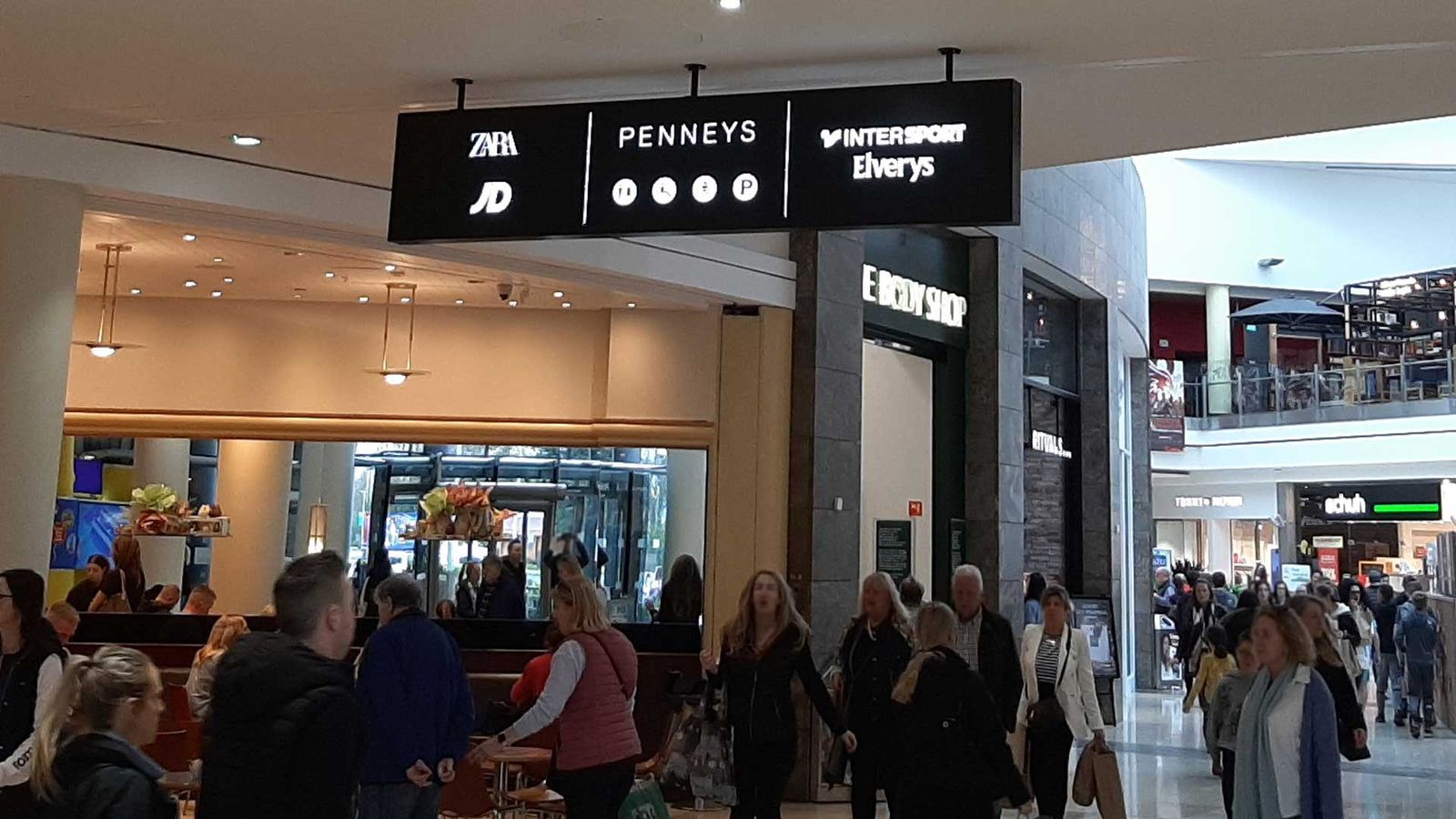 Hanging store directory sign above a busy shopping centre