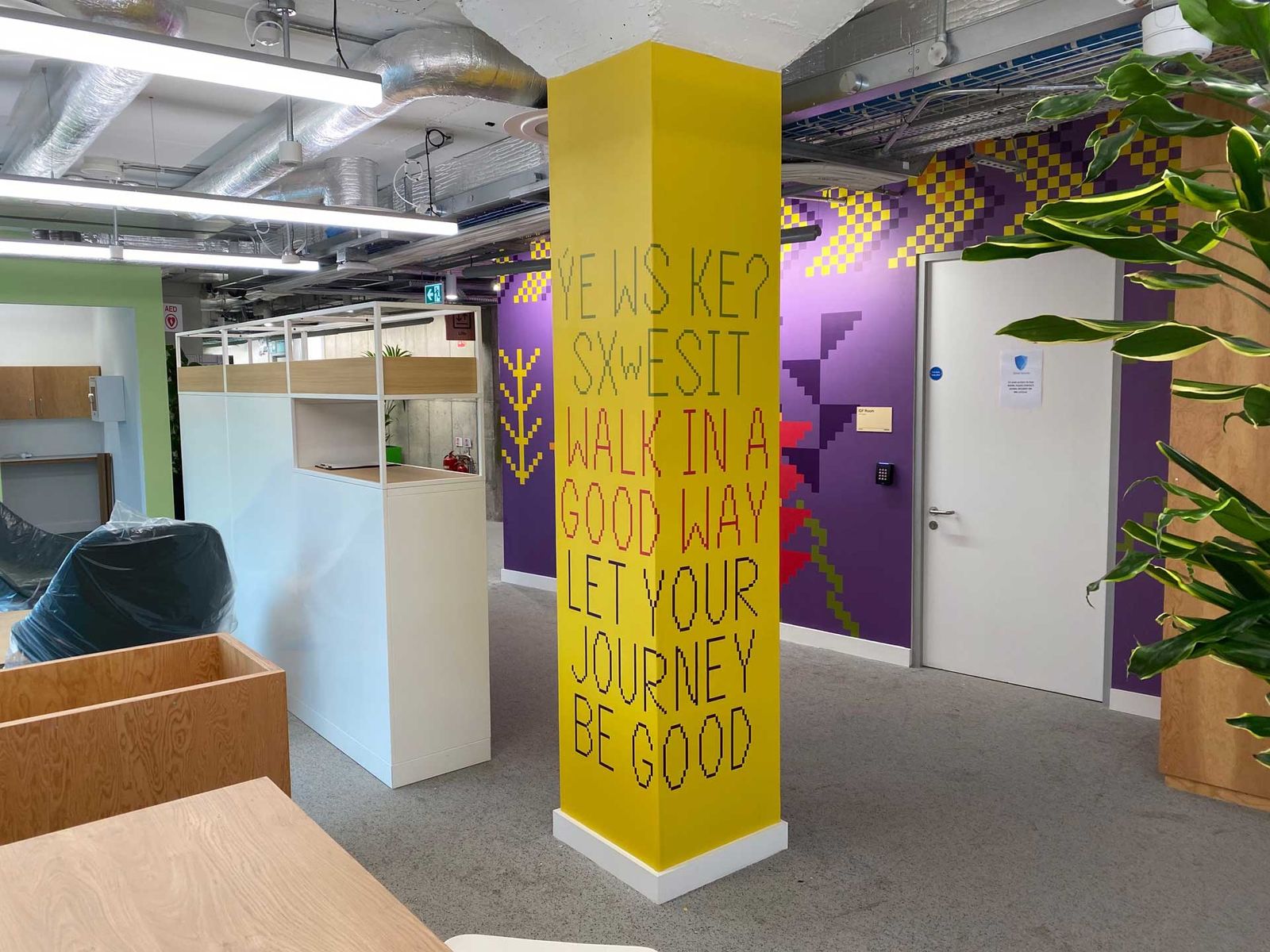 Yellow column lettered with a phrase about walking, beside purple and green graphic walls